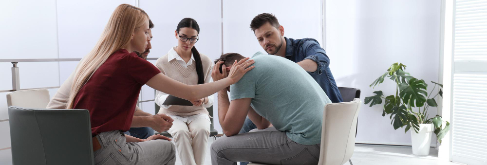 A group of employees is seen trying to console a distressed coworker in an office space.